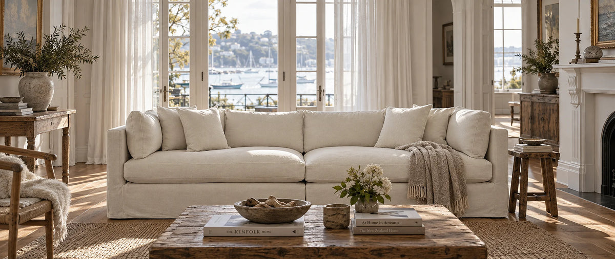 The Boathouse: Hamptons coastal living room with white timber beams, linen-striped sofa, and wide glass doors.