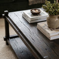 Millhouse Coffee Table in solid fir with walnut stain, low profile and open lower shelf, with books and vase.