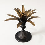Brass Palm Candle Holder with sculptural palm leaves radiating above a dark pedestal base.