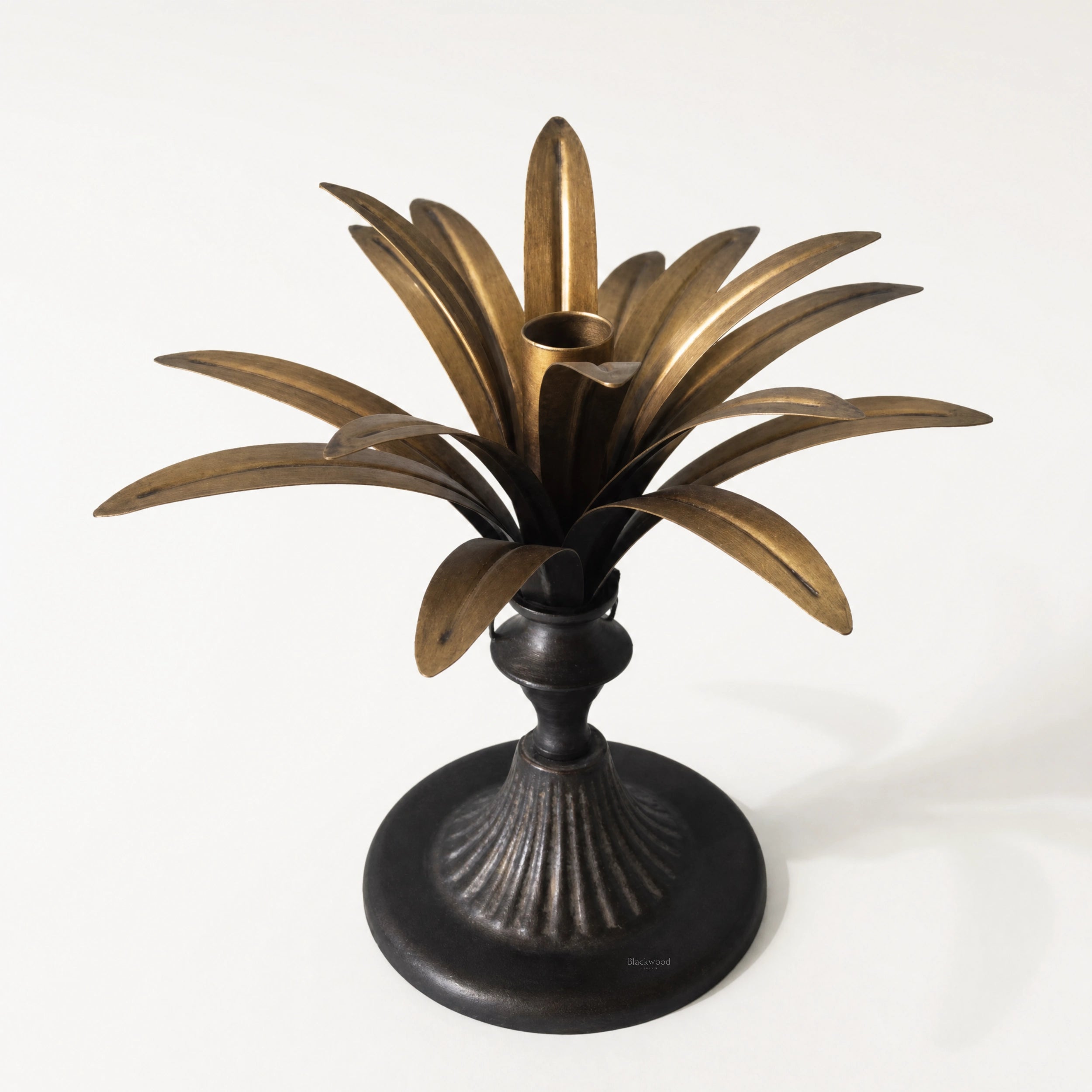 Brass Palm Candle Holder with sculptural palm leaves radiating above a dark pedestal base.