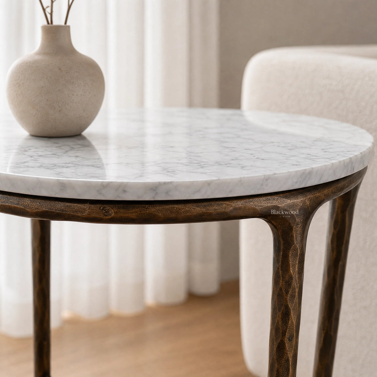 Montclair Marble Side Table with round white marble top and sculptural iron base, beige vase on top.