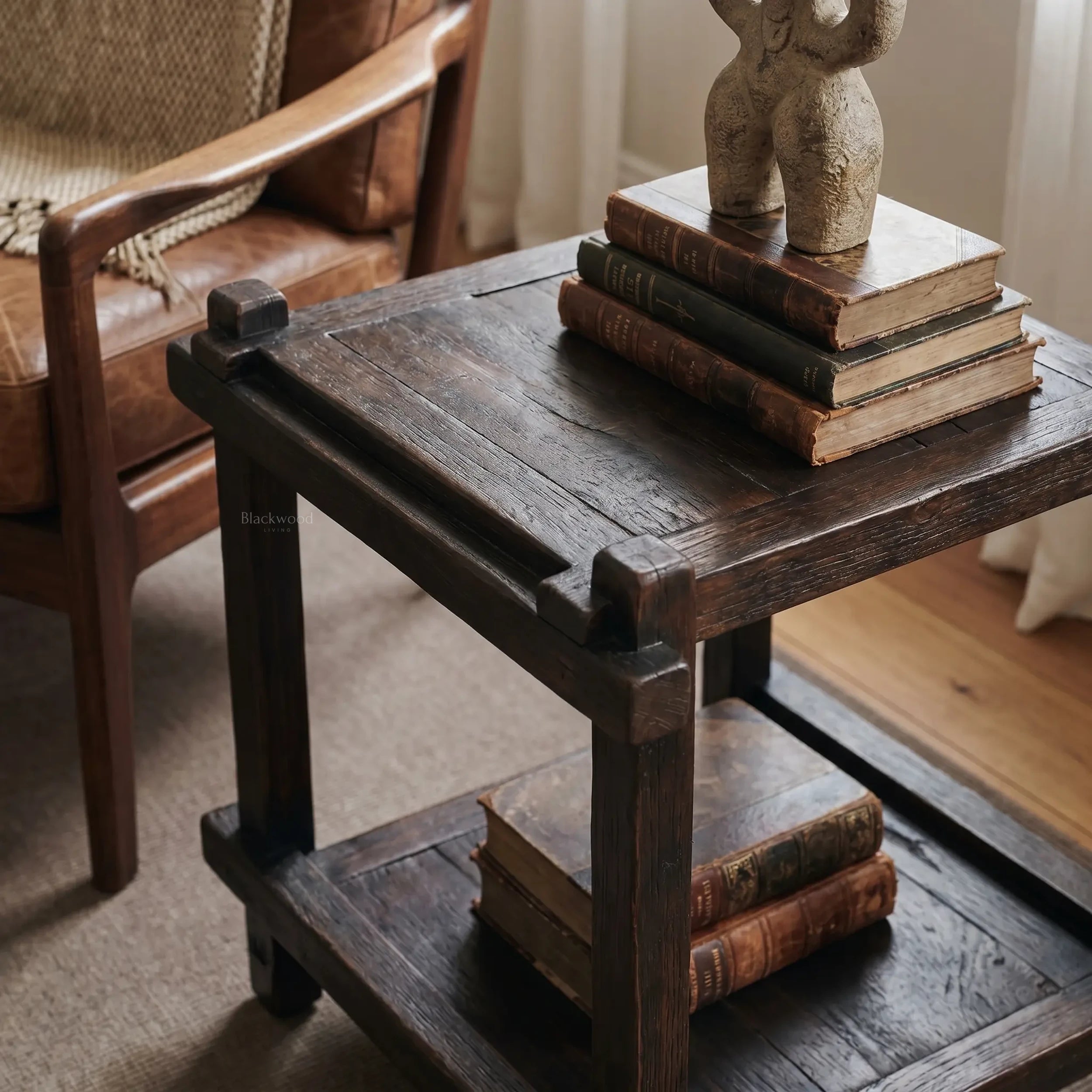 Millhouse Side Table in solid fir with exposed joinery, dark finish, beside stacked books and a stone sculpture