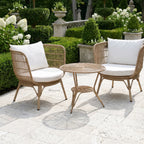 Clifton Outdoor 3-Piece Setting: wicker chairs with white cushions on a stone patio amid lush garden greenery