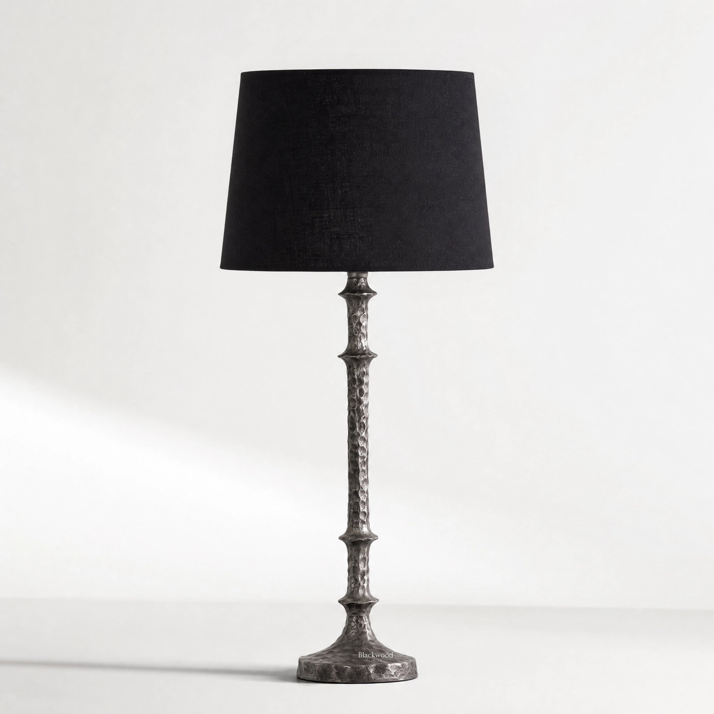 Backthorne Table Lamp with sculptural forged-looking hammered metal stem and black shade.