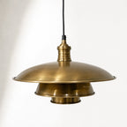 The Mercantile Brass Pendant hanging from a black cord with antique brass finish, vintage workshop-inspired lighting.