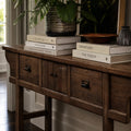 The Raffles Console in aged elm with rich grain, paired with a ceramic planter and stacked books.