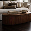 Reed Coffee Table in front of a sofa; round old elm table with deeply fluted timber detailing and a curved silhouette.