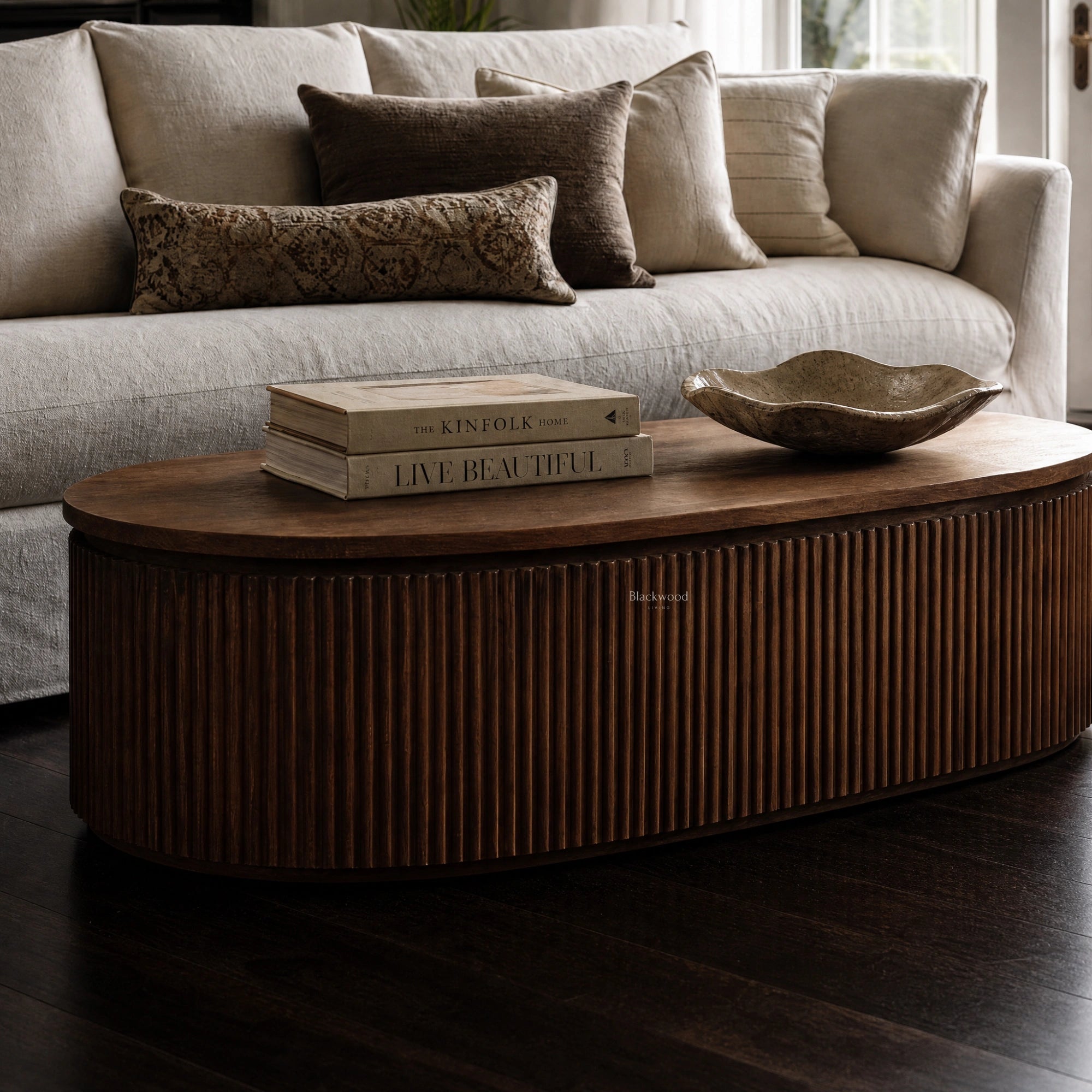 Reed Coffee Table in front of a sofa; round old elm table with deeply fluted timber detailing and a curved silhouette.