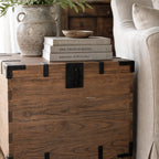 Avignon Trunk Table in reclaimed oak with exposed timber grain and forged metal details, beside books and a ceramic bowl.