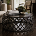 Mara Coffee Table: round iron lattice base with Plantation-inspired, artisan metalwork, shown with books and a plant.