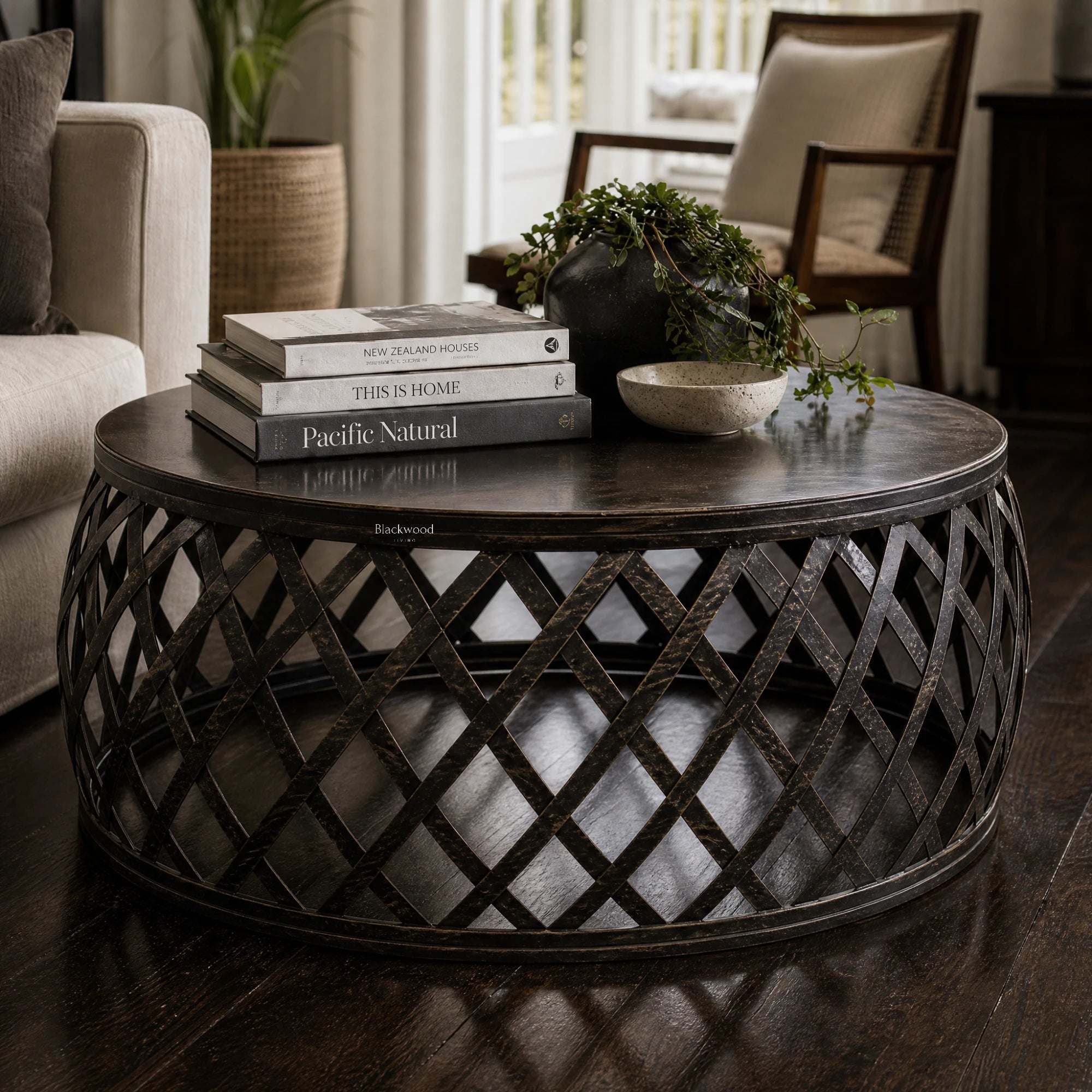 Mara Coffee Table: round iron lattice base with Plantation-inspired, artisan metalwork, shown with books and a plant.