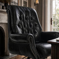 The Merchant Chair Estate Black leather armchair with nailhead trim in a study-like home office.