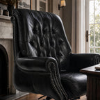 The Merchant Chair Estate Black leather armchair with nailhead trim in a study-like home office.