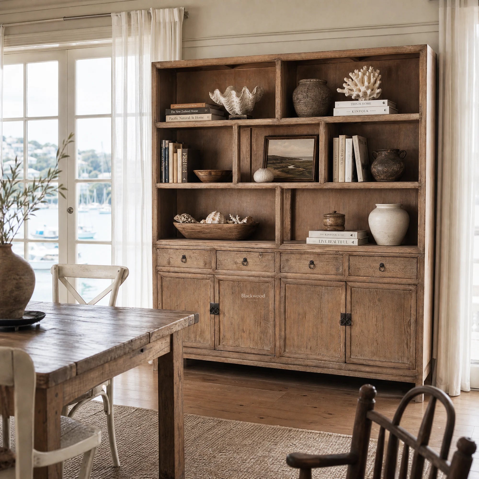 Fairhaven Wall Unit in weathered pine with open shelves displaying books, shells, and pottery.