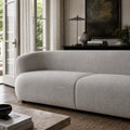 Amani Sofa with softly curved silhouette and textured upholstery in a calm, inviting living room setting.