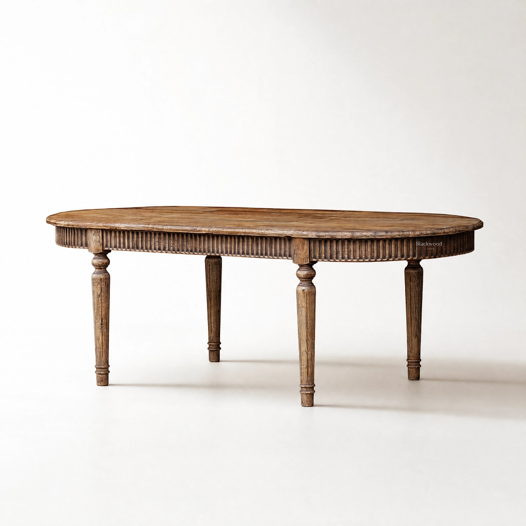 Loire Dining Table in reclaimed elm with weathered finish, carved apron, and turned legs.