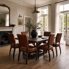 Beaumont Dining Chair - Vintage Tobacco leather, set around a dark wood dining table in a bright, sunlit dining room.