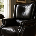 Beaumont Armchair in Estate Black leather, close-up of curved back with grain texture and nailhead trim.