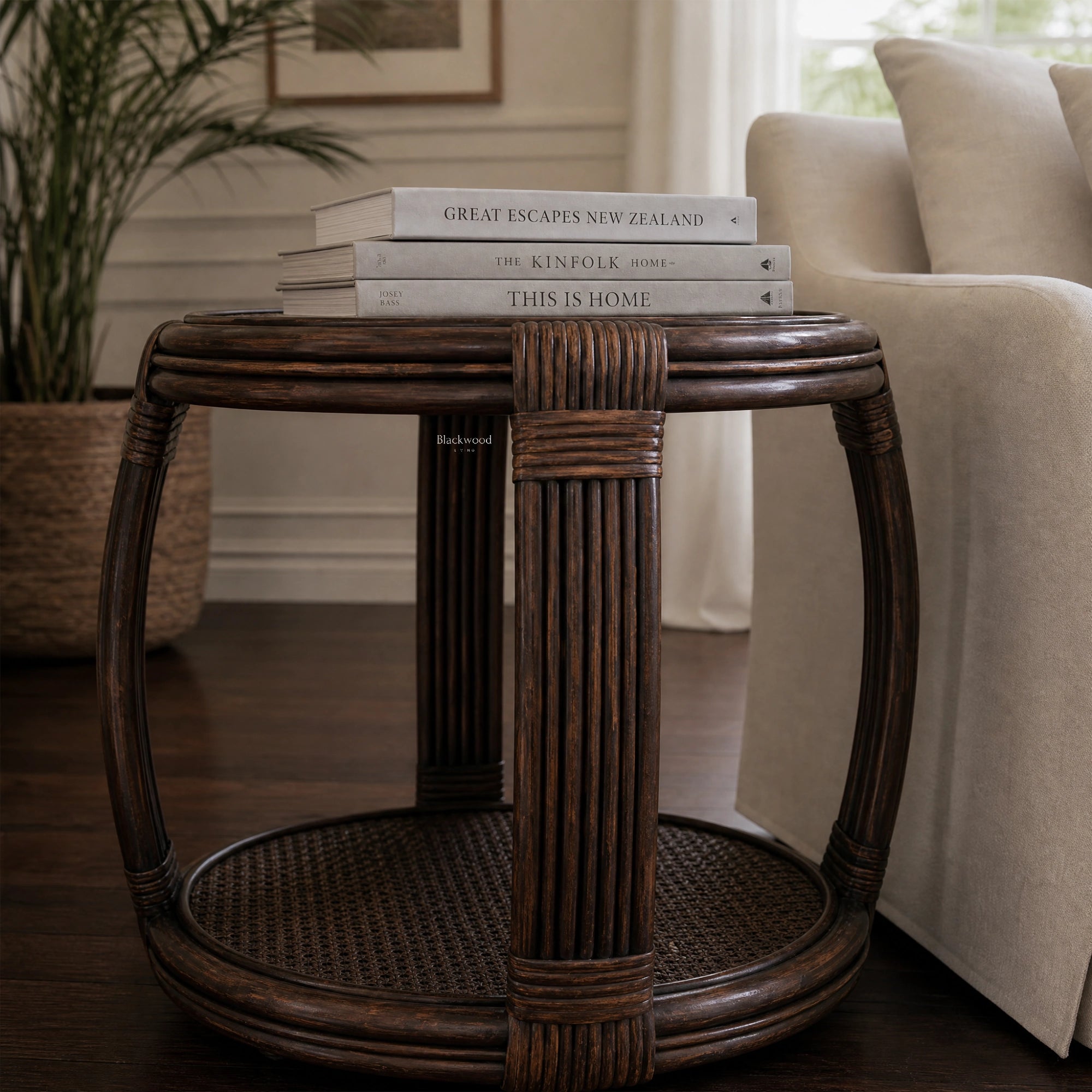 Havana Side Table: handwoven rattan with curved silhouette and warm texture, shown with books in a living room.