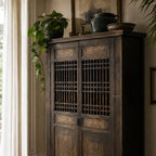 Shanghai Cabinet in weathered reclaimed pine with lattice doors and timeworn finish, topped by a plant and rustic pots.