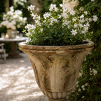 Versaille Urn planter with white blossoms in a weathered marble-look outdoor urn
