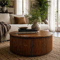 Reed Round Coffee Table in a living room, reclaimed elm drum with vertical fluting and a greenery centerpiece.