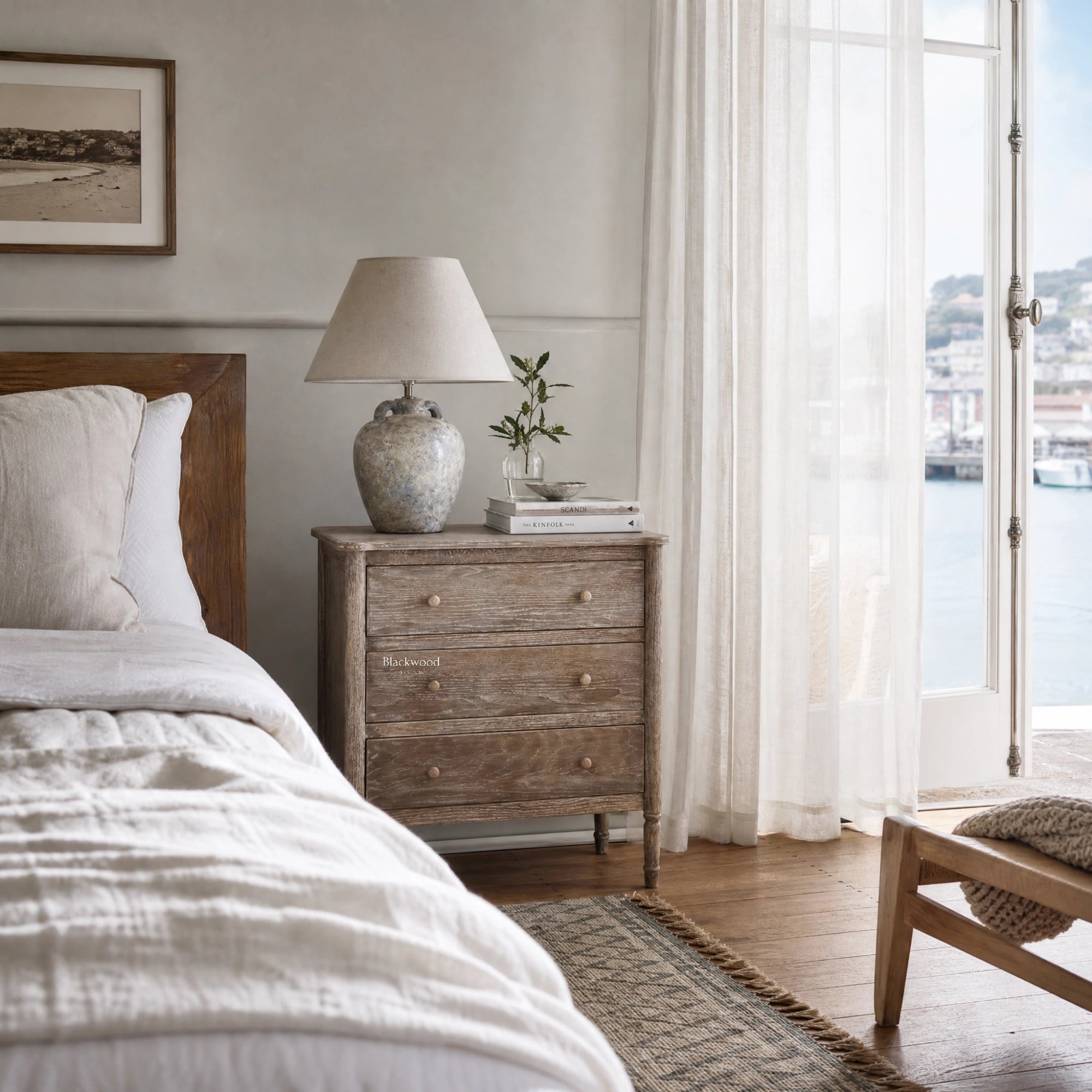 Saltwood Bedside Table beside bed with lamp, books, and plant in a coastal washed oak bedroom.