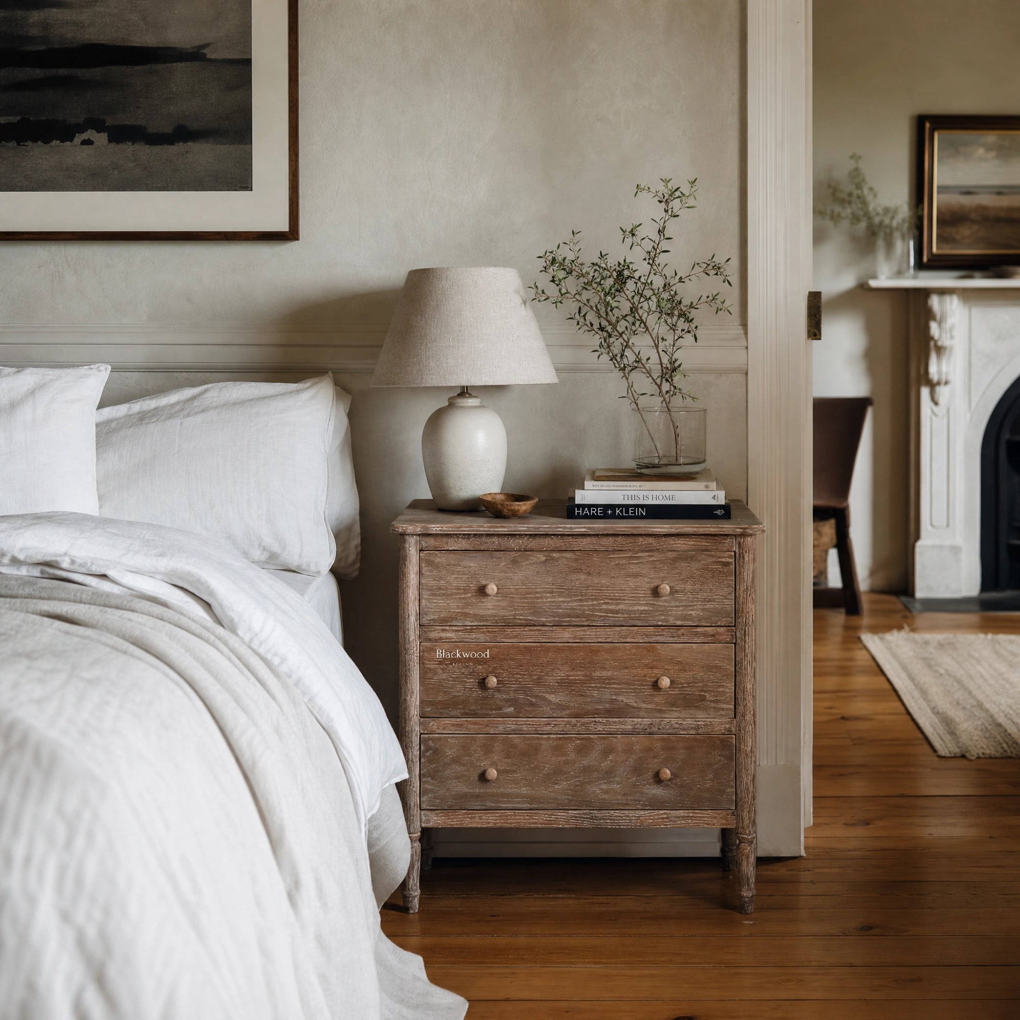 Saltwood Bedside Table in washed oak with weathered, ridged detailing beside a lamp and greenery.