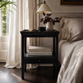 Colombo Bedside Table in a dark alder finish with lamp, vase and books in a neutral bedroom.