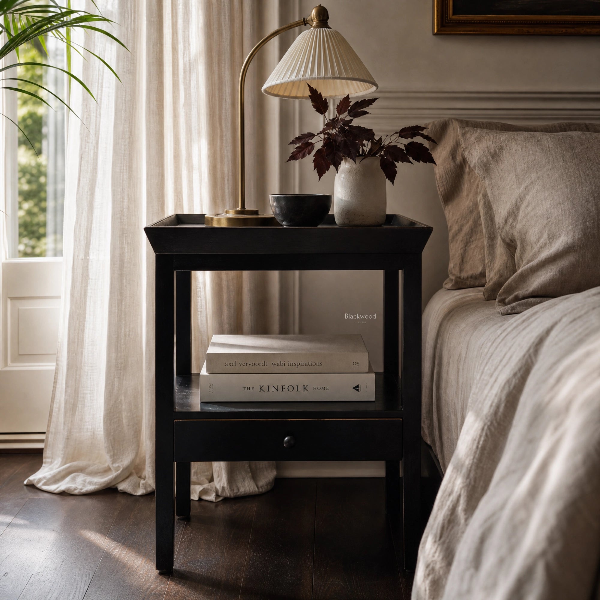 Colombo Bedside Table in a dark alder finish with lamp, vase and books in a neutral bedroom.