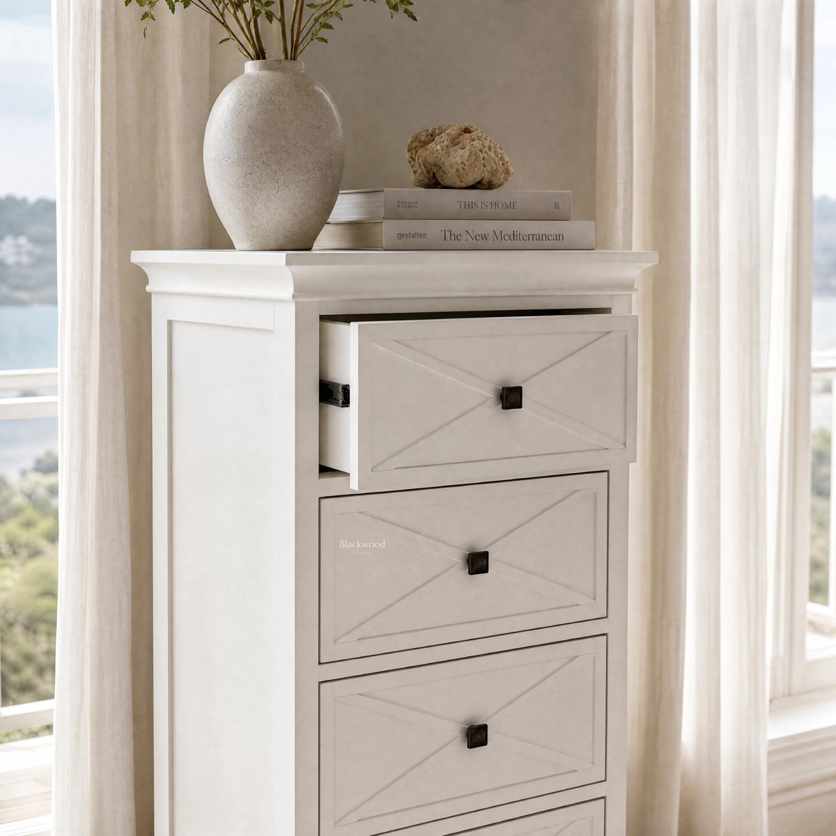 Bayview Tall Dresser - White with cross-panel drawers, topped by vase and stacked books.