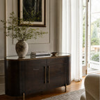 Meridian Sideboard in dark mango wood with brass accents and curved silhouette in a sunlit living room.