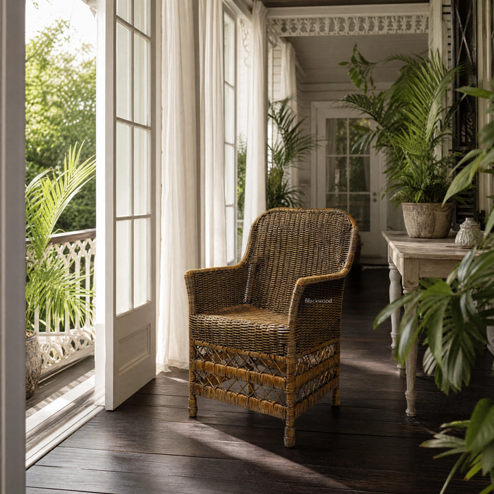Malacca Accent Chair, natural rattan with plantation style, on sunlit veranda beside white-framed doors and plants.