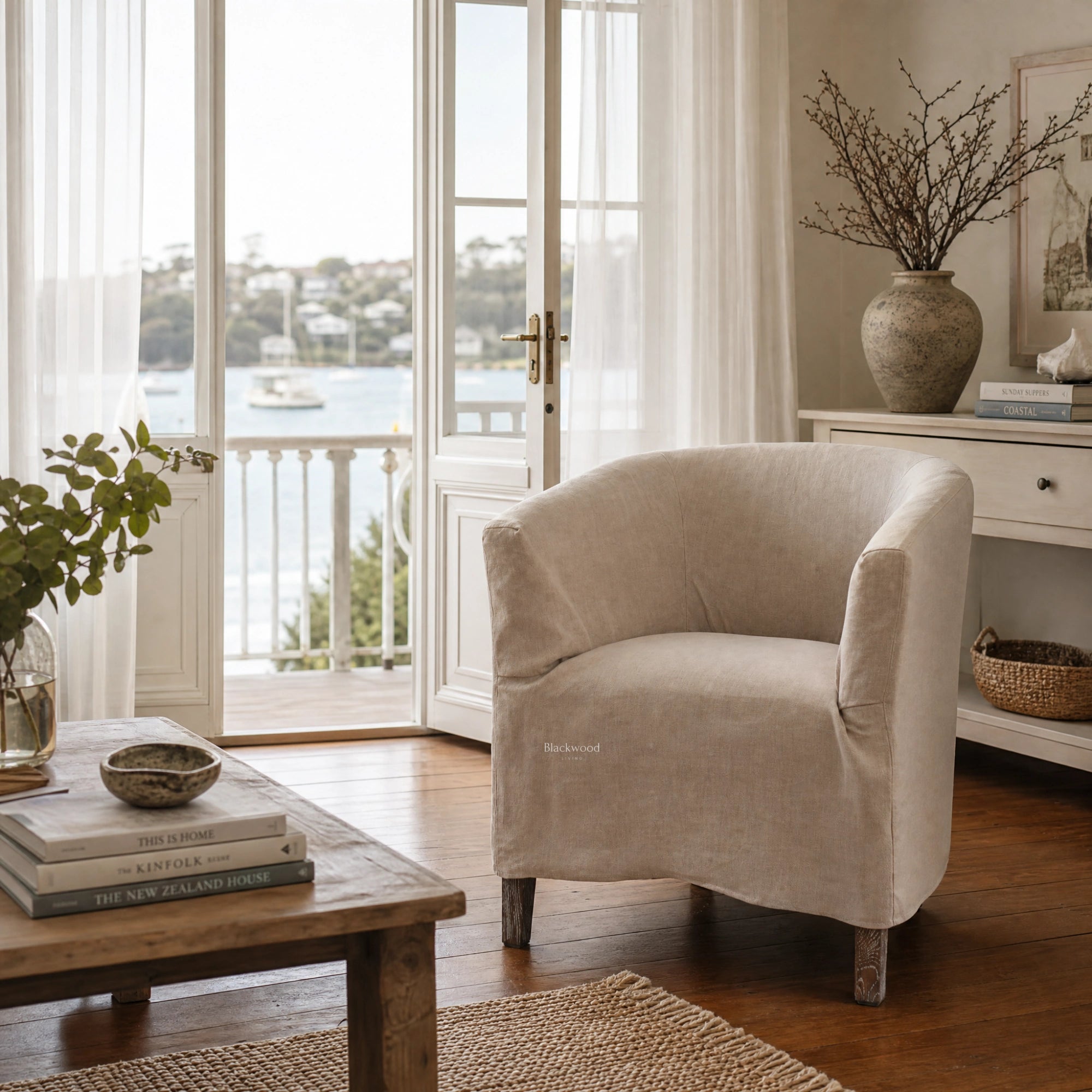 Stonehaven Accent Chair with linen slipcover, curved silhouette, and solid timber frame in a coastal living room.