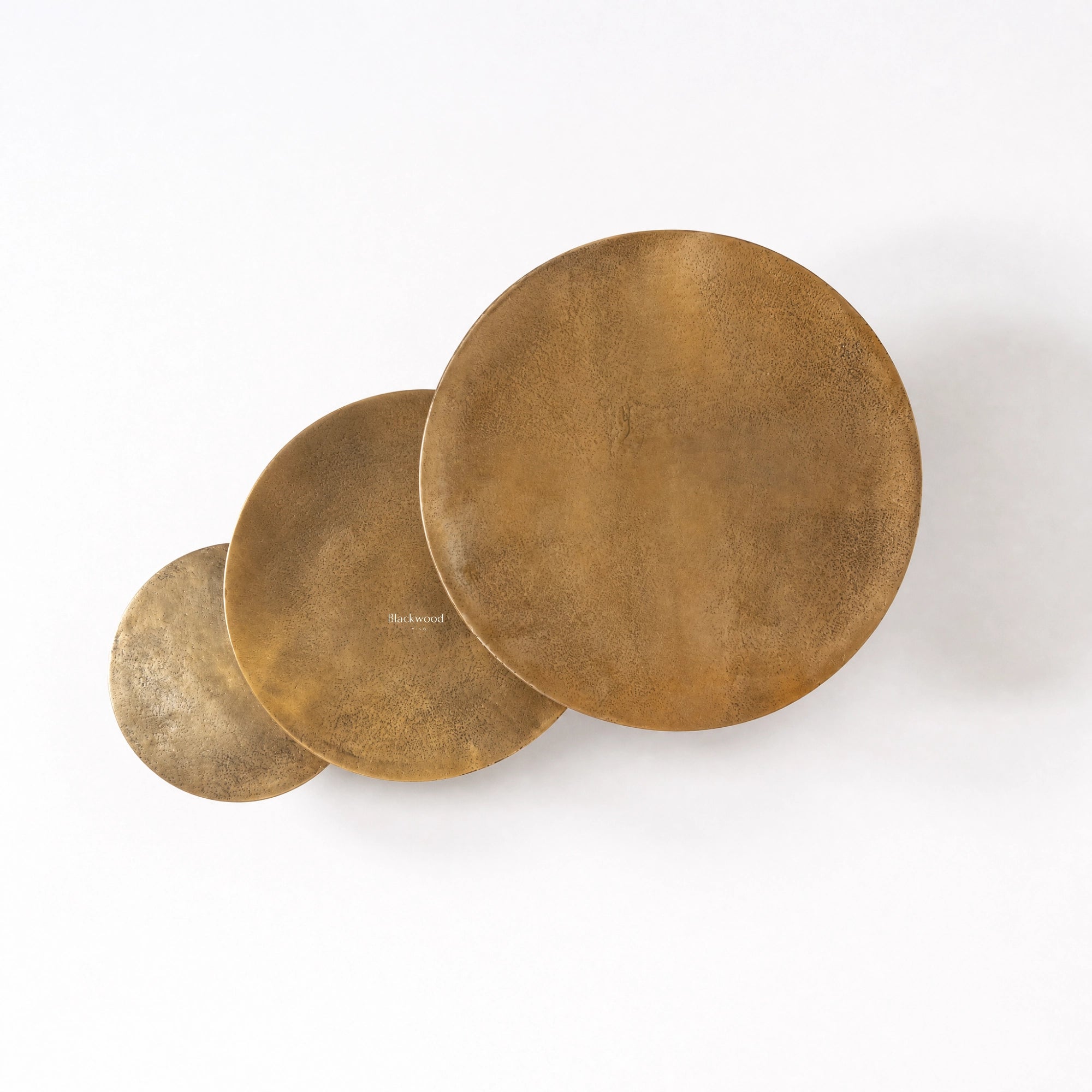 Calcutta Nesting Side Tables Set/3: three circular brass-toned tables with slender iron frames and aged aluminium tops.