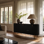 Valmont Curved Buffet in a dark finish with fluted panels and aged brass feet, in a sunlit living room.
