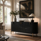 Valmont Curved Buffet in black with fluted panels and aged brass feet beside a large framed landscape painting.