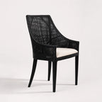 Barbados Dining Chair: black woven rattan with curved back and beige cushioned seat.