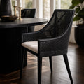 Barbados Dining Chair: black woven rattan with curved back and arms, cream seat cushion in dining room.