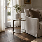 Belgrave Side Table - Brass with two clear glass surfaces and slender iron frame in a neutral living room.