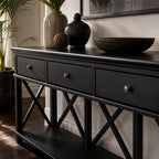 Bridgeport 3-Drawer Console in black with cross-braced legs and decorative vessels on top.