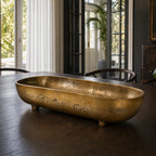 Madras Footed Bowl in antique brass finish, textured aluminium, on dark wood dining table.