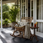 Sika Originals Monet Rattan Rocking Chair on a sunlit veranda, surrounded by greenery and a cozy throw blanket.