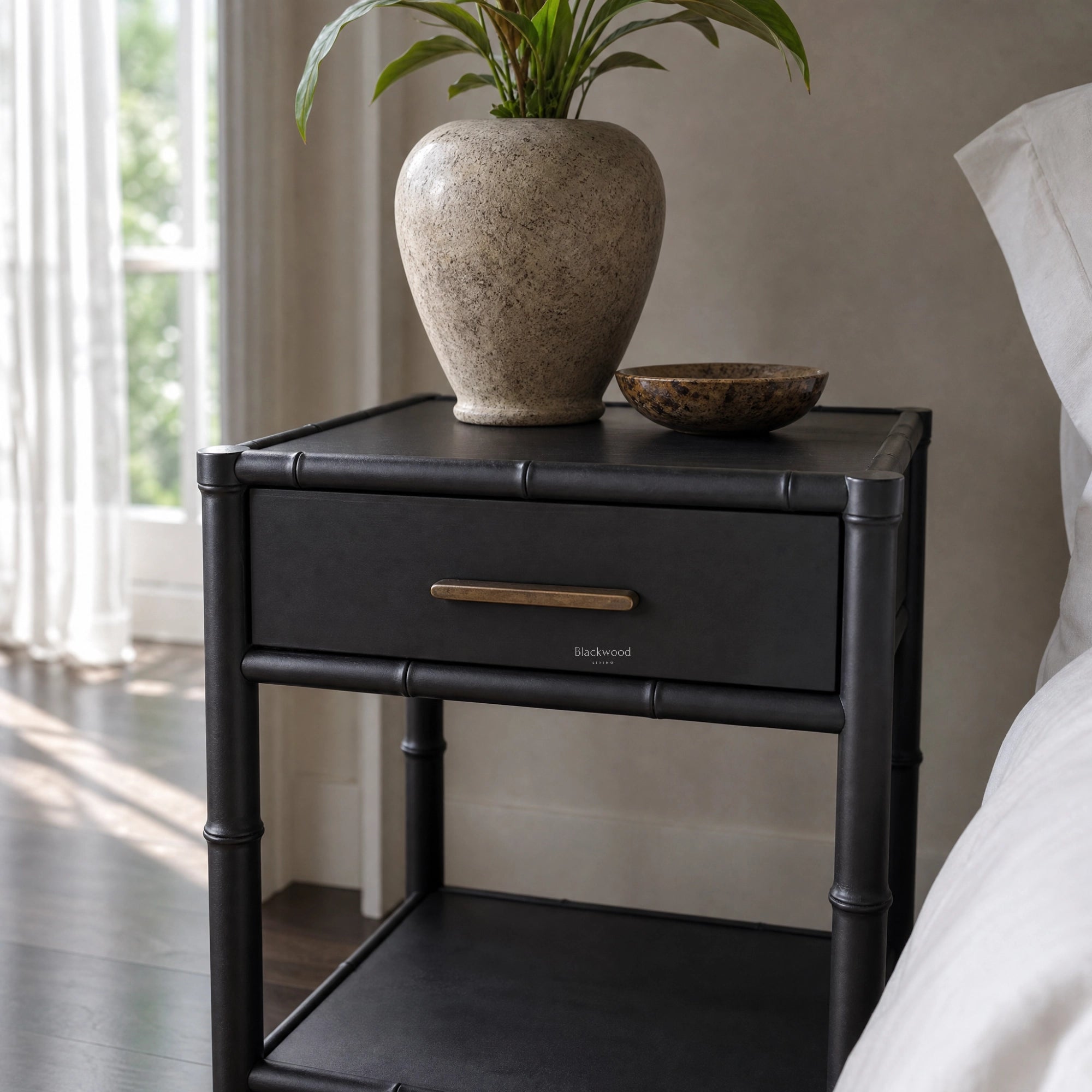 Rangoon Bedside Table - Black with a speckled vase holding a green plant and a decorative bowl.