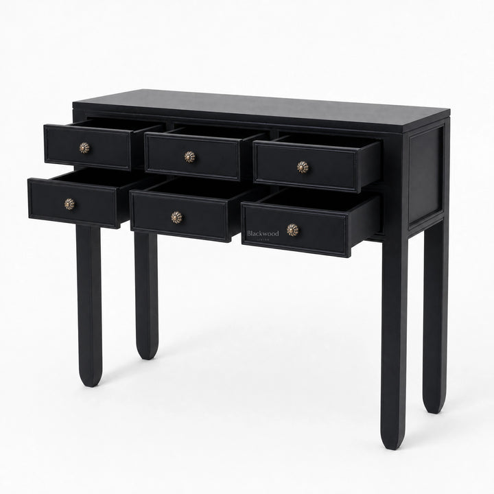 Black Penang hall table with slender legs and six open drawers featuring warm-toned metal handles for entryway storage.