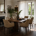 Woven rattan Malabar dining chairs with solid timber frames arranged around a wooden table in a sunlit plantation-style room.