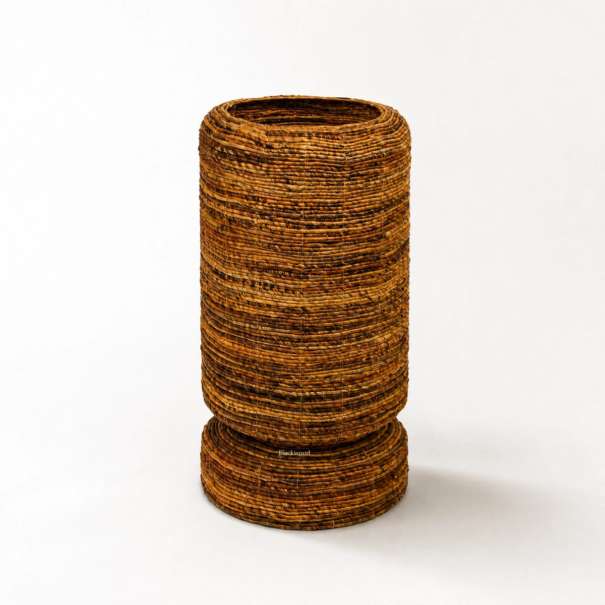 Large woven Ceylon planter with rounded form and textured banana leaf construction, featuring a pedestal base for tropical home decor.