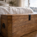 Reclaimed elm storage trunk with prominent wood grain and simple black metal hardware, offering a nautical, old-world aesthetic.