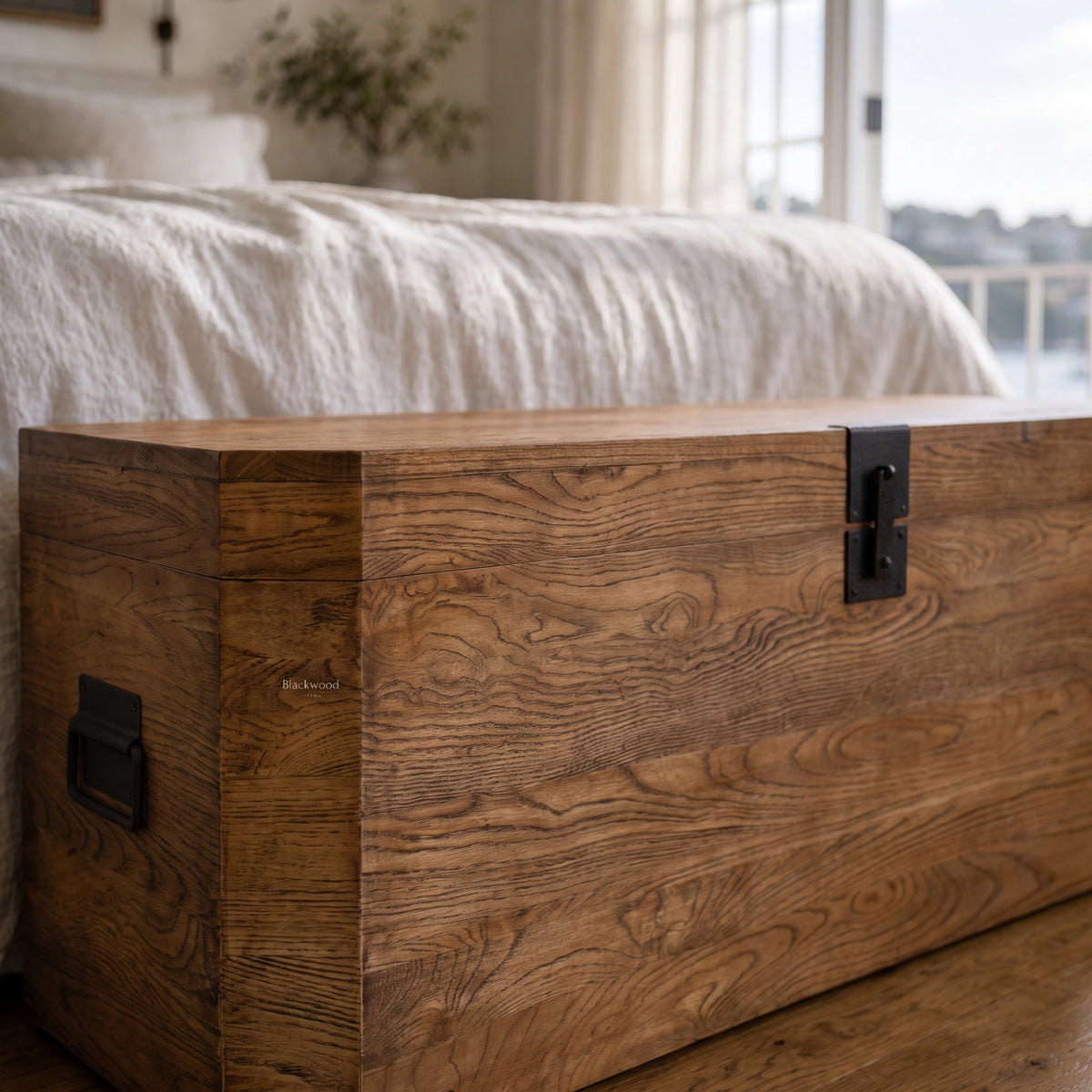 Reclaimed elm storage trunk with prominent wood grain and simple black metal hardware, offering a nautical, old-world aesthetic.