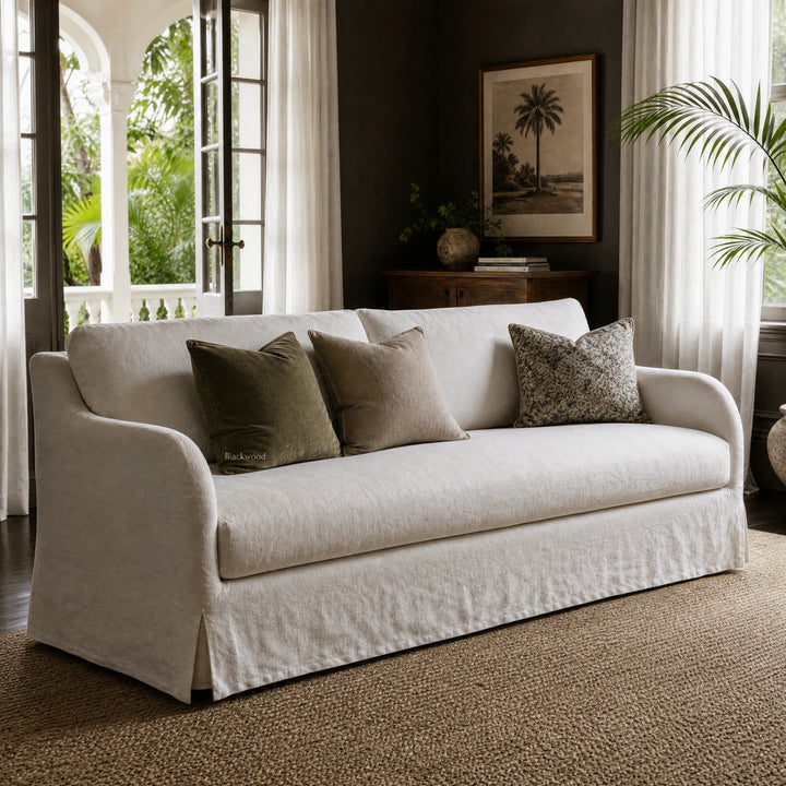 Monique Linen Slipcover Sofa with a full-length skirt and textured linen, neutral cushions in a sunlit living room.